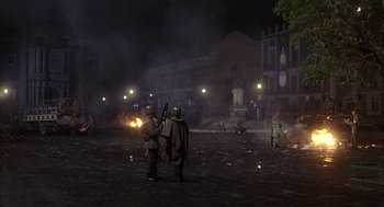 Movie still from “Missing” (1982), directed by Costa-Gavras – A group of men standing on top of a dirt field at night; Extreme Wide shot, High angle