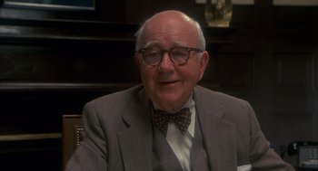 Movie still from “Missing” (1982), directed by Costa-Gavras – An older man wearing a suit and a bow tie; Close Up shot, Over the shoulder angle