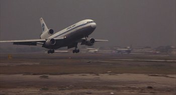 Movie still from “Missing” (1982), directed by Costa-Gavras – An airplane taking off from an airport runway; Extreme Wide shot, Low angle