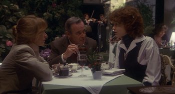 Movie still from “Missing” (1982), directed by Costa-Gavras – Three people are sitting at a table with wine glasses; Medium shot, Over the shoulder angle