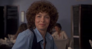 Movie still from “Missing” (1982), directed by Costa-Gavras – A woman in a blue shirt is posing for a picture; Close Up shot, Over the shoulder angle