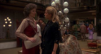 Movie still from “Missing” (1982), directed by Costa-Gavras – Two women standing next to each other in front of a chandelier; Medium shot, Over the shoulder angle
