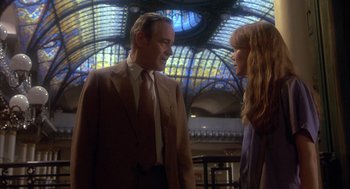 Movie still from “Missing” (1982), directed by Costa-Gavras – A man and a woman standing next to each other in front of a stained - glass window; Medium shot, Low angle