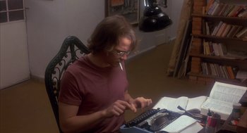 Movie still from “Missing” (1982), directed by Costa-Gavras – A man sitting at a table typing on a typewriter; Medium shot, Low angle