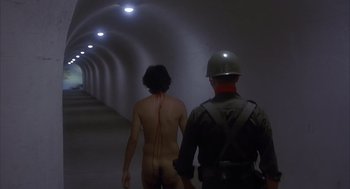 Movie still from “Missing” (1982), directed by Costa-Gavras – A naked man walking in a tunnel with an officer; Wide shot, High angle