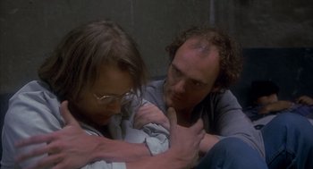 Movie still from “Missing” (1982), directed by Costa-Gavras – A man and a woman sitting on the ground; Close Up shot, High angle