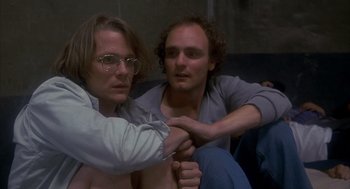 Movie still from “Missing” (1982), directed by Costa-Gavras – Two men sitting on a couch and one of the men has his arm around the other man; Close Up shot, High angle