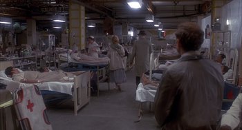 Movie still from “Missing” (1982), directed by Costa-Gavras – A group of people sitting around a room; Wide shot, High angle