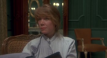 Movie still from “Missing” (1982), directed by Costa-Gavras – A woman sitting in a chair holding a book; Close Up shot, Over the shoulder angle