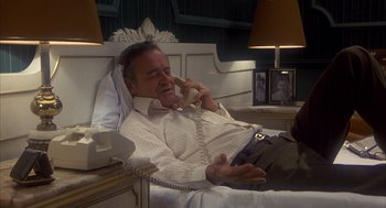 Movie still from “Missing” (1982), directed by Costa-Gavras – A man sitting in a bed talking on a phone; Medium shot, High angle