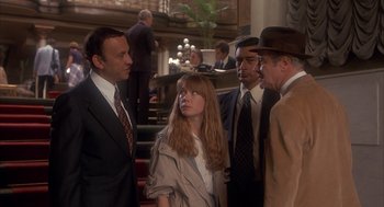 Movie still from “Missing” (1982), directed by Costa-Gavras – A group of people standing in a room talking to each other; Medium shot, Over the shoulder angle