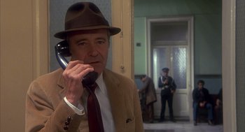Movie still from “Missing” (1982), directed by Costa-Gavras – An older man wearing a hat talking on a phone; Close Up shot, Low angle