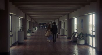 Movie still from “Missing” (1982), directed by Costa-Gavras – A man and a woman walking down a hall way; Wide shot, High angle
