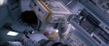Movie still from “Mission to Mars” (2000), directed by Brian De Palma – An image of a person in a spacesuit in a room; Medium shot, Overhead angle