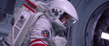 Movie still from “Mission to Mars” (2000), directed by Brian De Palma – A man in a spacesuit is putting on a helmet; Medium shot, Overhead angle