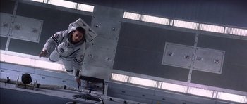 Movie still from “Mission to Mars” (2000), directed by Brian De Palma – A man standing on top of an airplane in a hangar; Wide shot, Overhead angle