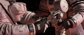 Movie still from “Mission to Mars” (2000), directed by Brian De Palma – Two people in space suits are holding a gun; Close Up shot, Overhead angle
