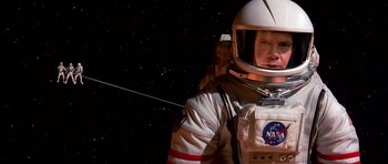 Movie still from “Mission to Mars” (2000), directed by Brian De Palma – A man in a spacesuit and helmet in the dark; Medium shot, Overhead angle