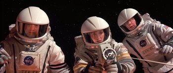 Movie still from “Mission to Mars” (2000), directed by Brian De Palma – A woman in a spacesuit holding a camera in front of another woman in a spacesuit; Medium shot, Overhead angle