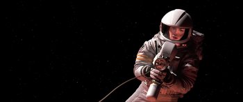 Movie still from “Mission to Mars” (2000), directed by Brian De Palma – A man in a spacesuit holding a device in his hand; Medium shot, Overhead angle