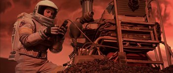 Movie still from “Mission to Mars” (2000), directed by Brian De Palma – A man in a white hard hat is holding a drill; Medium shot, Overhead angle