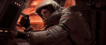 Movie still from “Mission to Mars” (2000), directed by Brian De Palma – A man in a spacesuit and helmet in front of an orange sky; Medium shot, Overhead angle