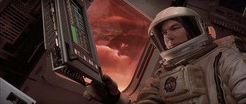 Movie still from “Mission to Mars” (2000), directed by Brian De Palma – A man in a spacesuit holding a computer screen; Medium shot, Low angle