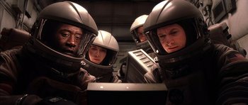 Movie still from “Mission to Mars” (2000), directed by Brian De Palma – A group of people wearing helmets looking at a computer screen; Medium shot, High angle