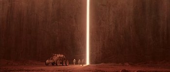 Movie still from “Mission to Mars” (2000), directed by Brian De Palma – A group of people standing next to a large rock wall; Extreme Wide shot, High angle