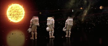 Movie still from “Mission to Mars” (2000), directed by Brian De Palma – A group of people in spacesuits standing in front of a space background; Wide shot, Overhead angle