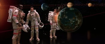Movie still from “Mission to Mars” (2000), directed by Brian De Palma – Two men in spacesuits standing next to each other in front of planets; Wide shot, Overhead angle