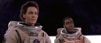 Movie still from “Mission to Mars” (2000), directed by Brian De Palma – A woman and a man in spacesuits in front of a space background; Medium shot, Low angle
