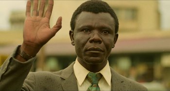 Movie still from “Mississippi Masala” (1991), directed by Mira Nair – A man in a suit and tie raising his right hand; Close Up shot, Low angle