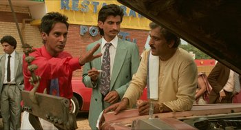 Movie still from “Mississippi Masala” (1991), directed by Mira Nair – A group of men standing next to each other near a building; Medium shot, Low angle