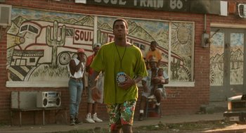 Movie still from “Mississippi Masala” (1991), directed by Mira Nair – A group of people standing in front of a building; Wide shot, Low angle
