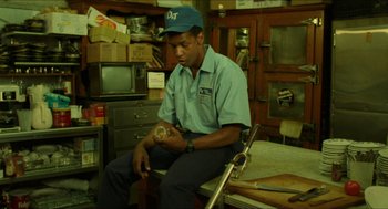 Movie still from “Mississippi Masala” (1991), directed by Mira Nair – A man sitting on a chair in a room; Medium shot, Low angle