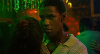 Movie still from “Mississippi Masala” (1991), directed by Mira Nair – A young man is standing in front of a green light; Close Up shot, Over the shoulder angle