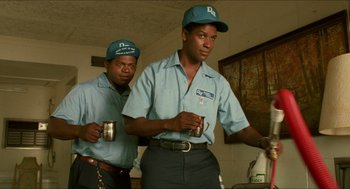 Movie still from “Mississippi Masala” (1991), directed by Mira Nair – A couple of men standing next to each other holding cups; Medium shot, Low angle