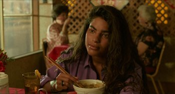 Movie still from “Mississippi Masala” (1991), directed by Mira Nair – A woman sitting at a table with a bowl of food; Close Up shot, High angle