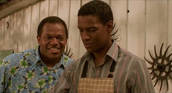 Movie still from “Mississippi Masala” (1991), directed by Mira Nair – Two men standing next to each other in front of a fence; Close Up shot, Over the shoulder angle