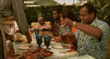 Movie still from “Mississippi Masala” (1991), directed by Mira Nair – A group of people sitting at a table with plates of food; Medium shot, High angle