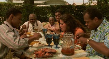 Movie still from “Mississippi Masala” (1991), directed by Mira Nair – A group of people sitting at a table eating food; Medium shot, High angle