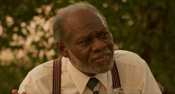 Movie still from “Mississippi Masala” (1991), directed by Mira Nair – An older man wearing a white shirt and a green tie; Close Up shot, Over the shoulder angle