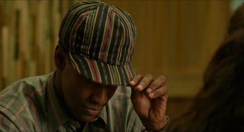 Movie still from “Mississippi Masala” (1991), directed by Mira Nair – A young man wearing a striped hat and a plaid shirt; Close Up shot, High angle