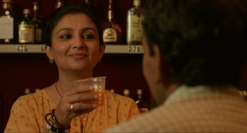Movie still from “Mississippi Masala” (1991), directed by Mira Nair – A woman is holding a glass in front of a man; Close Up shot, Low angle