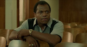 Movie still from “Mississippi Masala” (1991), directed by Mira Nair – A man sitting at a table with his arm resting on his chest; Close Up shot, Low angle