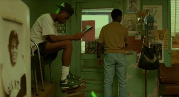 Movie still from “Mississippi Masala” (1991), directed by Mira Nair – Two young men are standing in front of a window; Wide shot, Low angle