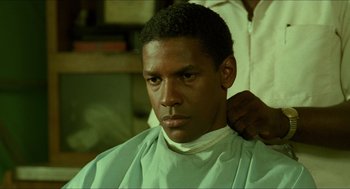 Movie still from “Mississippi Masala” (1991), directed by Mira Nair – A man getting his hair cut by another man; Close Up shot, Over the shoulder angle