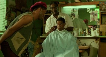 Movie still from “Mississippi Masala” (1991), directed by Mira Nair – A man getting his hair cut in a barber shop; Medium shot, Over the shoulder angle