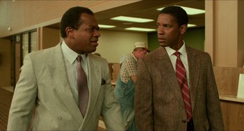 Movie still from “Mississippi Masala” (1991), directed by Mira Nair – Two men in suits talking to each other in an office; Medium shot, Low angle